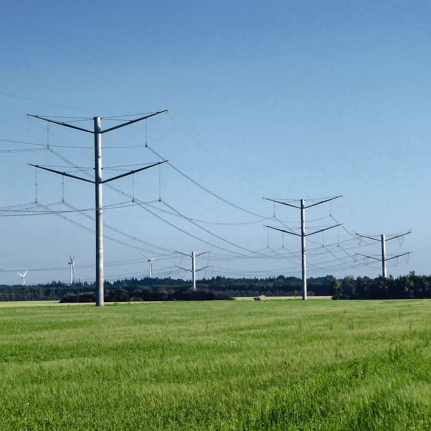 Overhead lines in nature on a green meadow with a blue sky